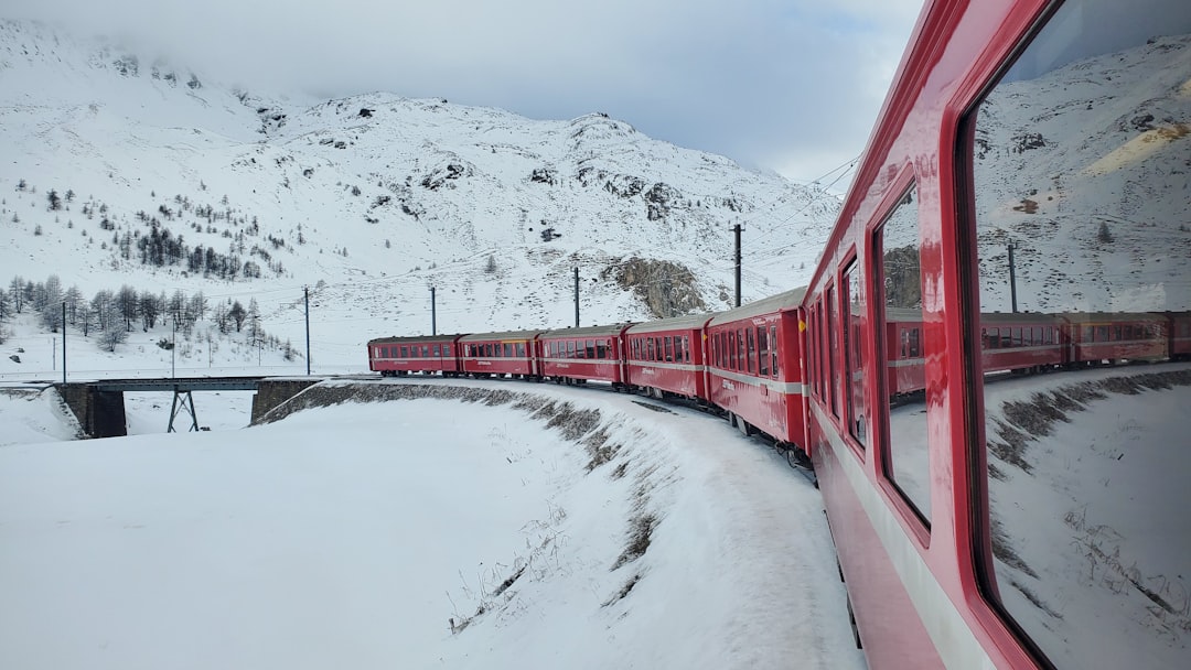 a red train traveling down train tracks next to a snow covered mountain