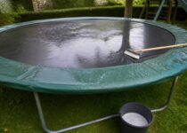 Trampoline in de tuin die wordt schoongemaakt met een zachte borstel