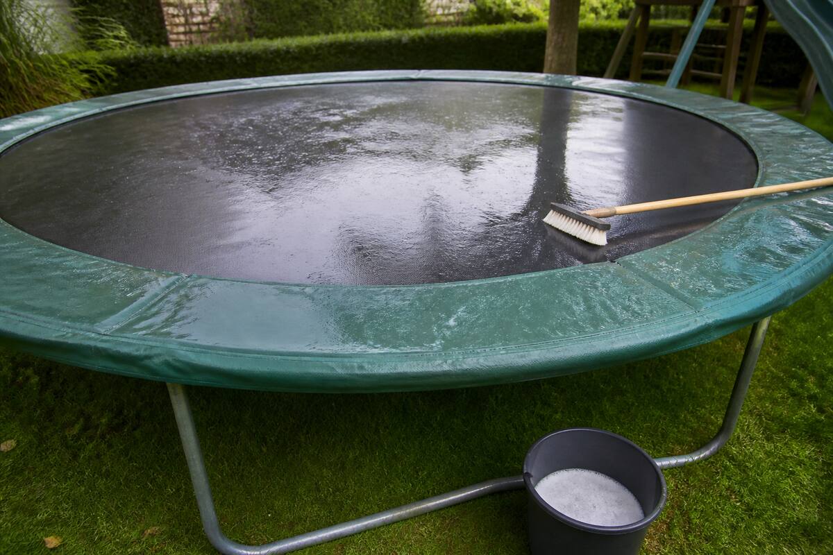 Trampoline in de tuin die wordt schoongemaakt met een zachte borstel