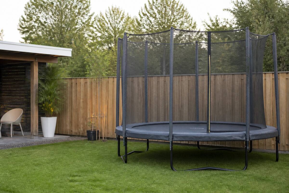 Trampoline met veiligheidsnet in een verzorgde achtertuin