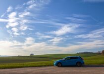 blue 5-door hatchback on asphalt road during daytime