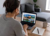 Iemand vergelijkt reisopties op een laptop met een notitieboekje